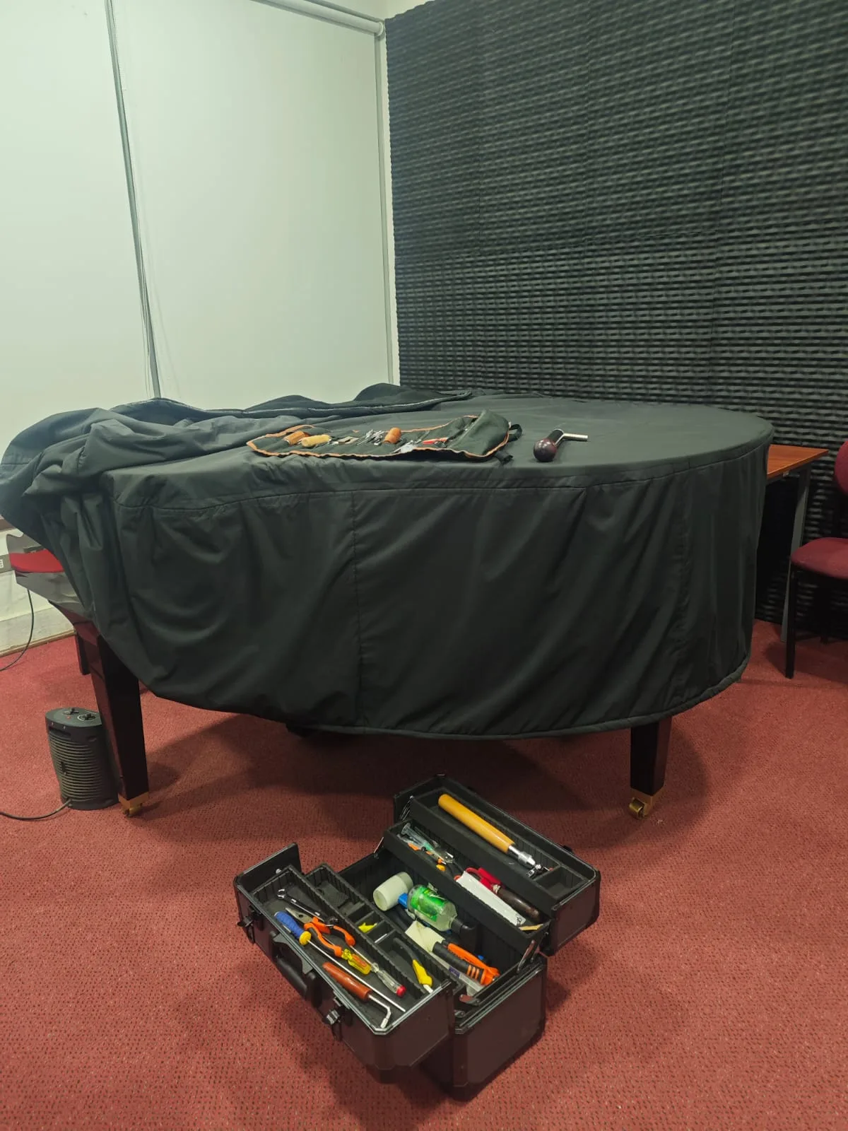 Herramientas profesionales de afinación junto a piano de cola en estudio acústico — tecnicopiano.cl