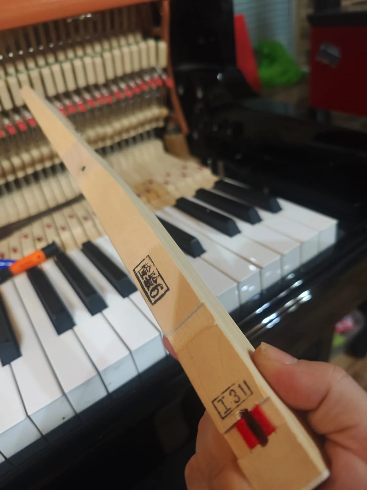 Inspección de palanca de madera del teclado durante reparación de piano — tecnicopiano.cl