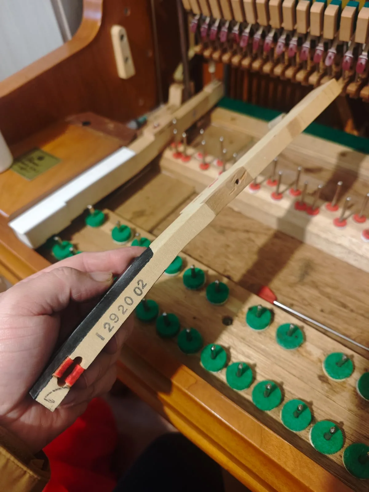 Palanca de tecla con número de serie inspeccionada durante reparación de piano — tecnicopiano.cl
